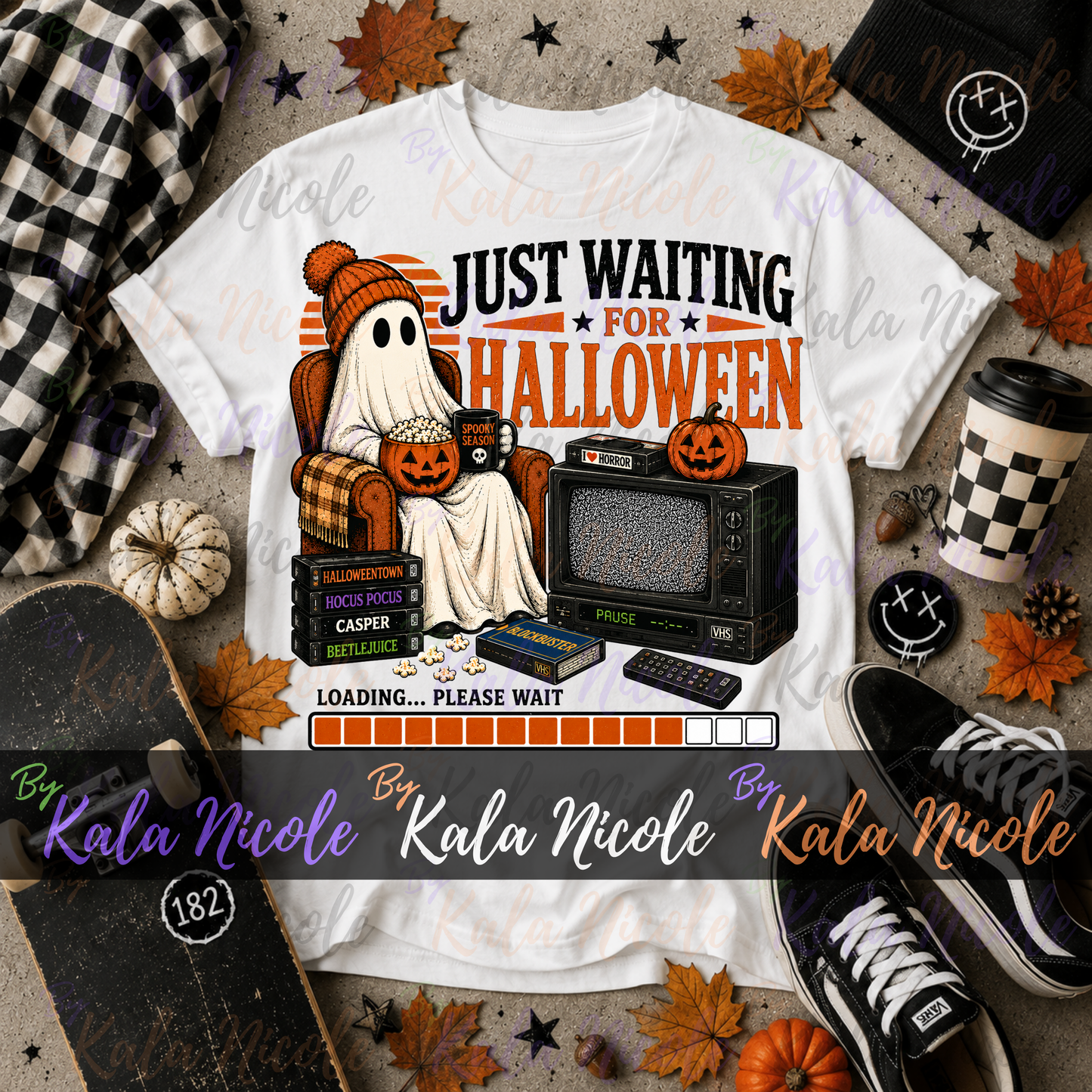 A white graphic T-shirt laid flat with Halloween-themed props around it, including a plaid scarf, skateboard, cup, sneakers, pumpkins, and autumn leaves. The shirt graphic shows a ghost in a pumpkin hat sitting in a plaid armchair next to a vintage TV, with text reading 'JUST WAITING FOR HALLOWEEN' and a loading bar.